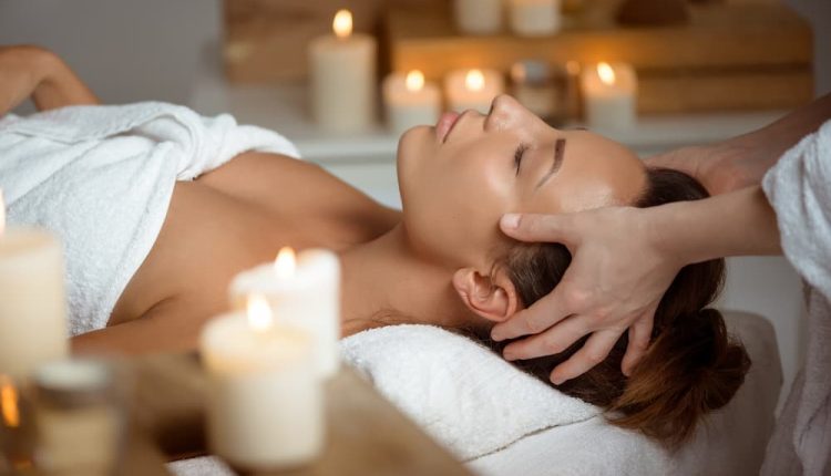 Jovem mulher com massagem de rosto relaxante no salão spa